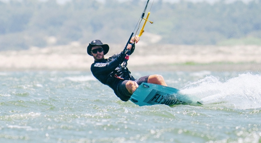 Praticante de kitesurf em manobra na água durante aula em Icaraizinho