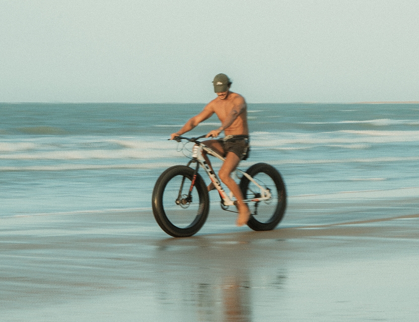 Turista con bicicleta en la playa de Icaraizinho, paseo disponible en el Club de Mar